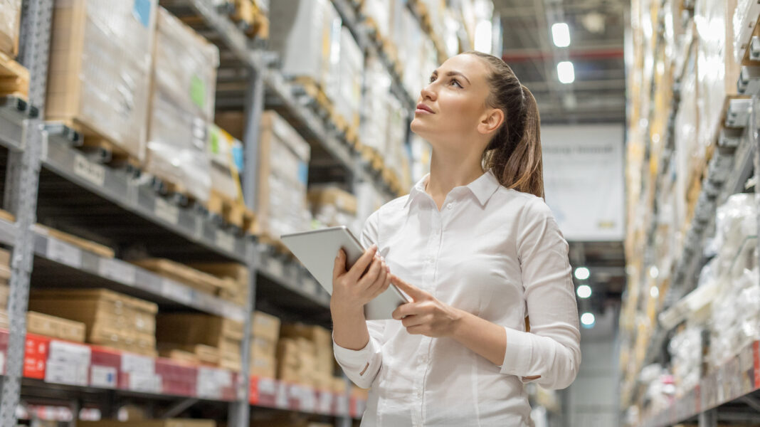 Frau, die durch ein Handelslager geht und sich Bestandsnotizen macht