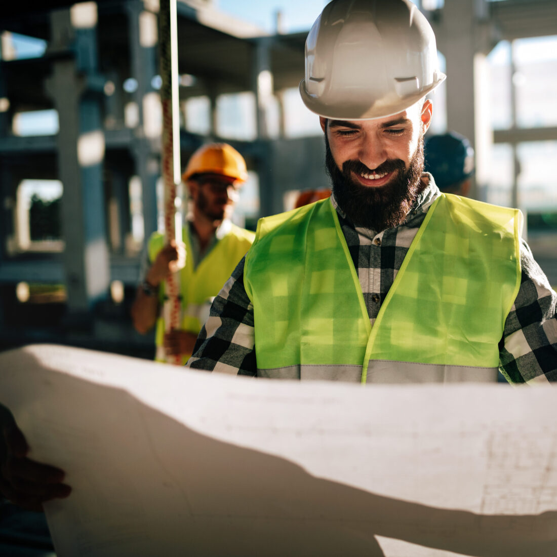 Zufriedener Ingenieur, der auf einer Baustelle zufrieden auf seine Planmessungen schaut