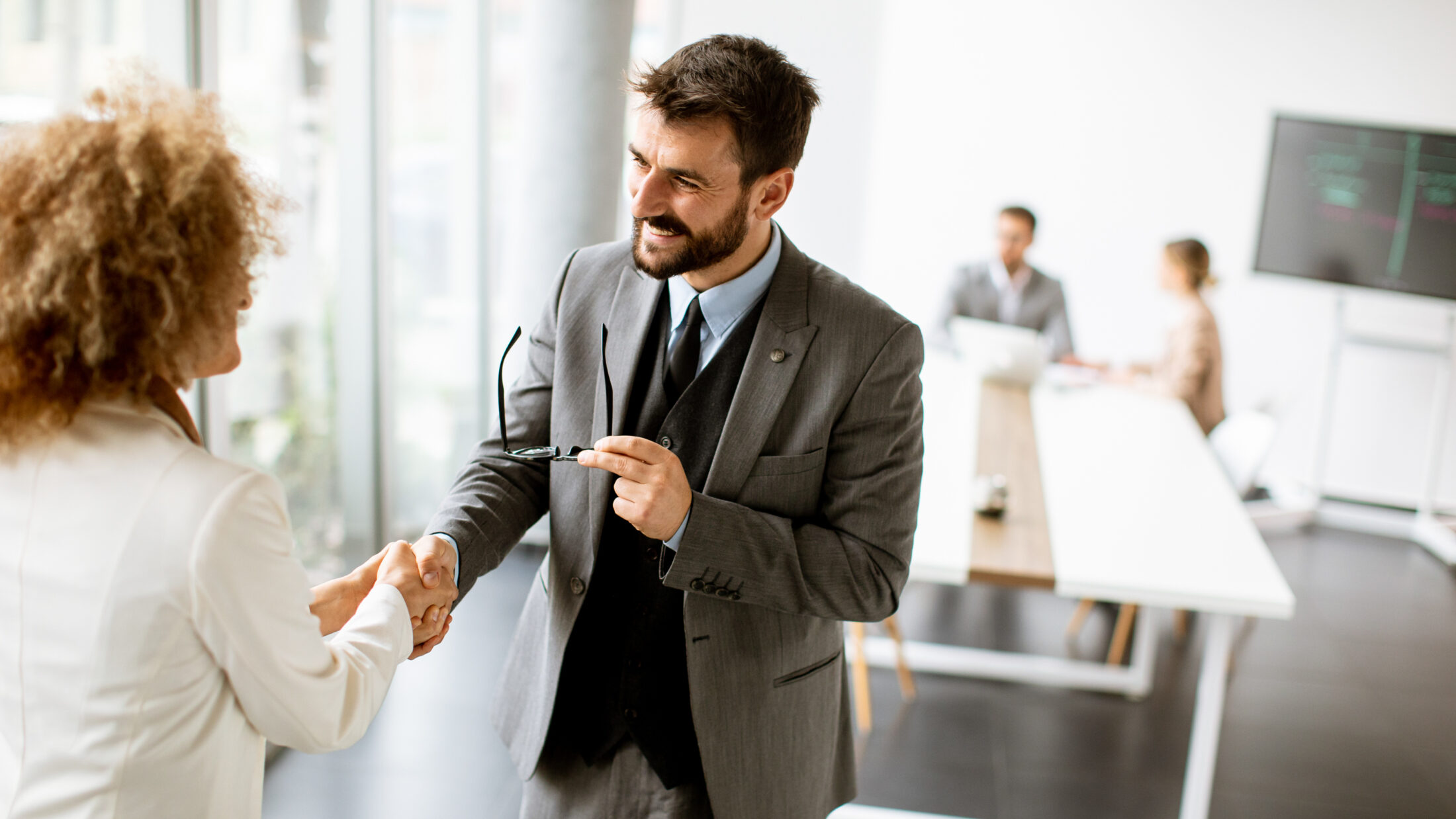 Ein paar gut aussehende multiethnische Geschäftsleute schütteln sich im Büro die Hände