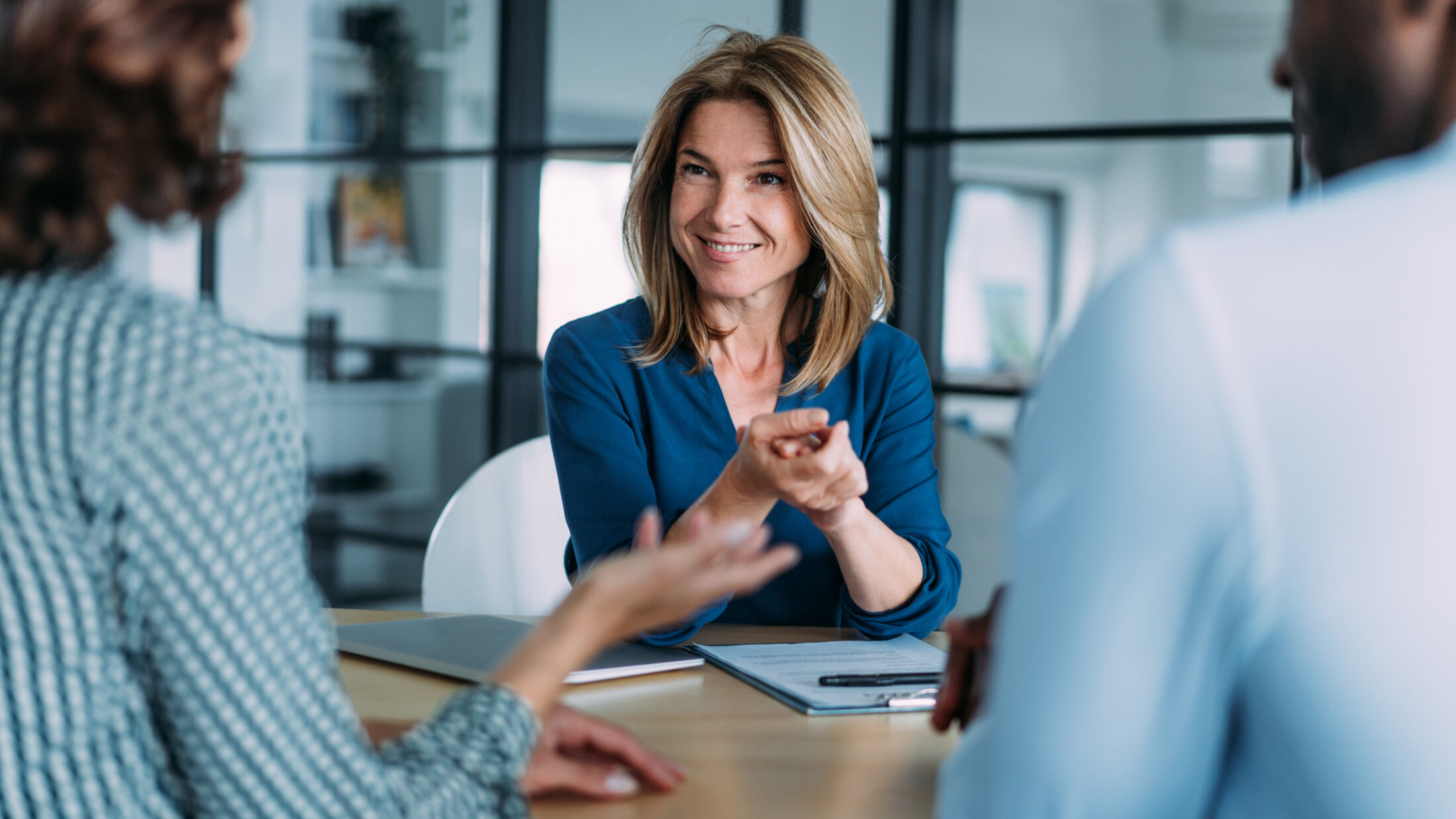 Shot of group of business persons in business meeting. Three persons on meeting in board room. Business team on meeting in modern office. Female manager discussing with her colleagues.