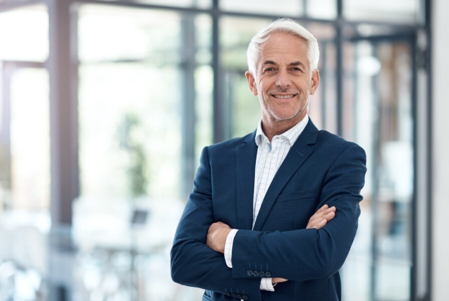 Porträt eines selbstbewussten reifen Geschäftsmannes, der in einem modernen Büro arbeitet