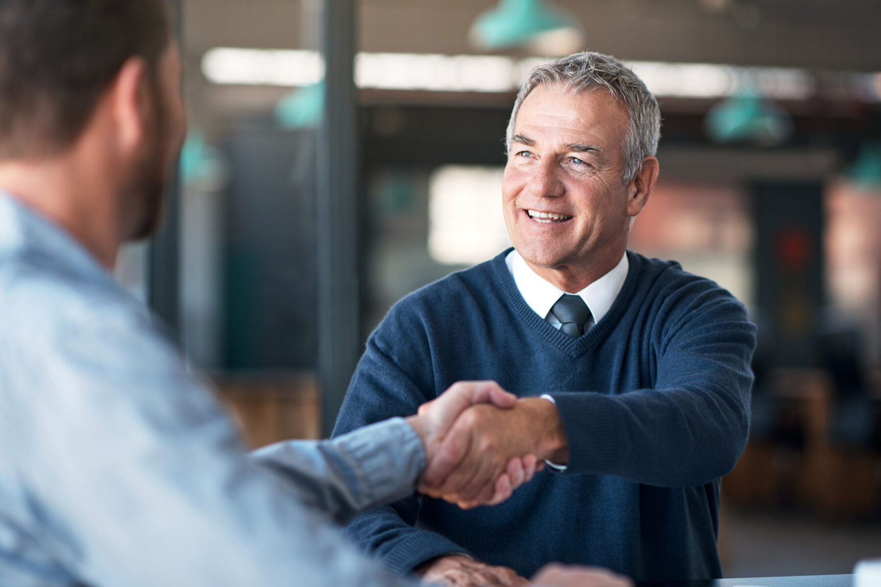 Zwei Männer im Business-Look schütteln sich lächelnd die Hände