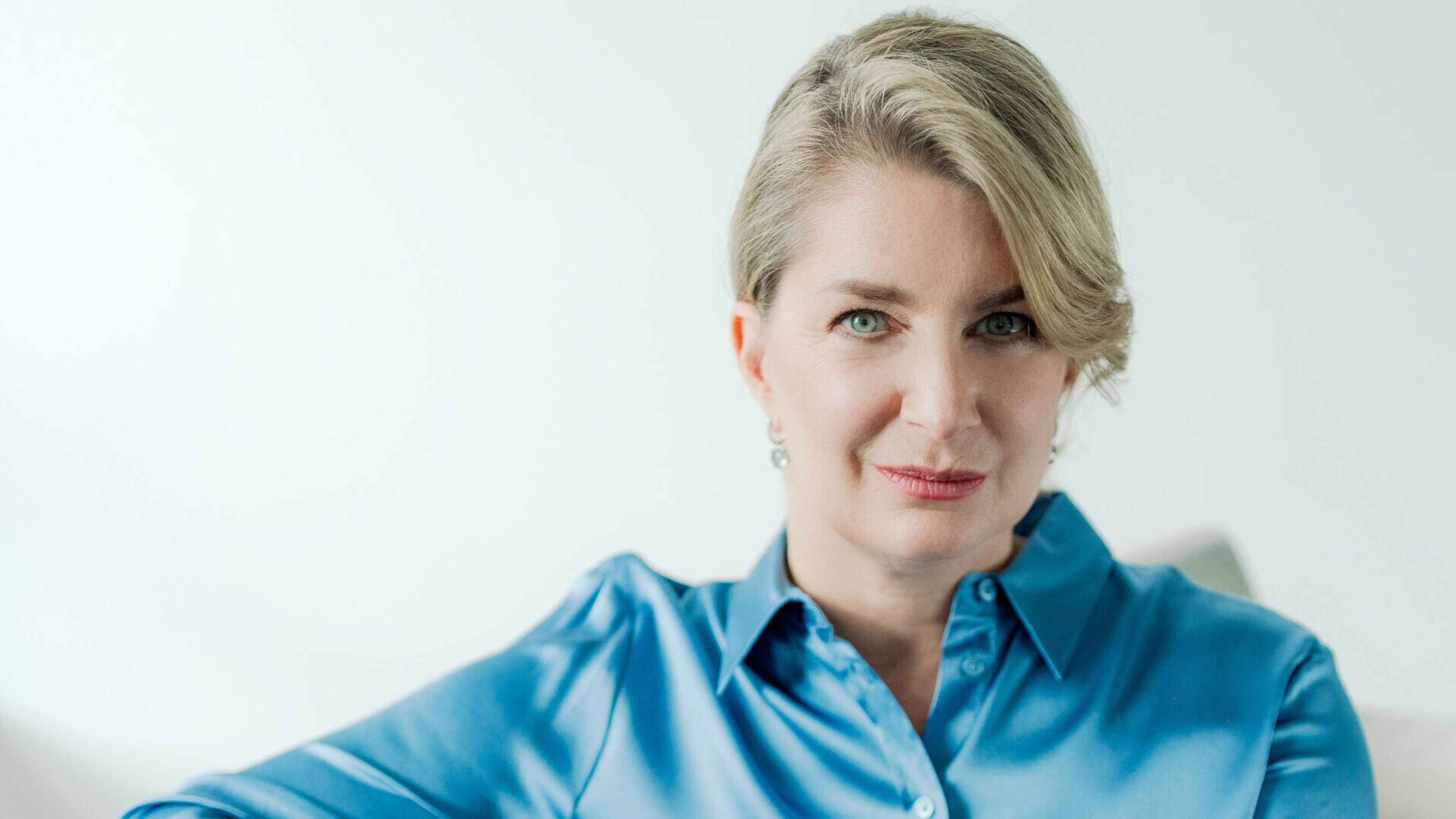 Frau sitzt auf einem Sofa und blickt in die Kamera